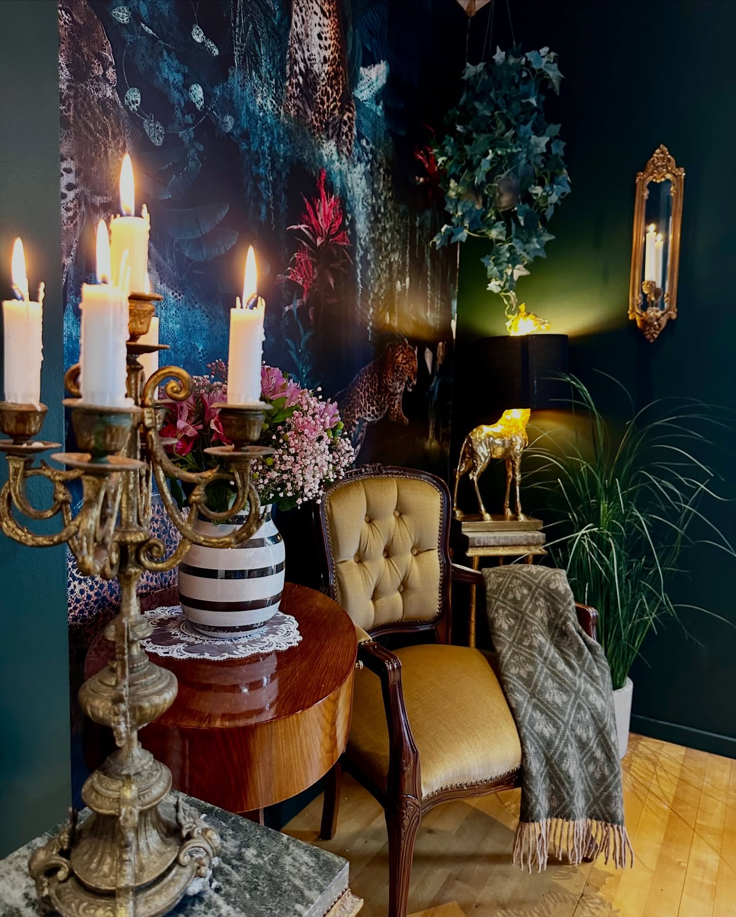 Candelabro decorato con candele accese accanto a una poltrona dorata con una coperta.