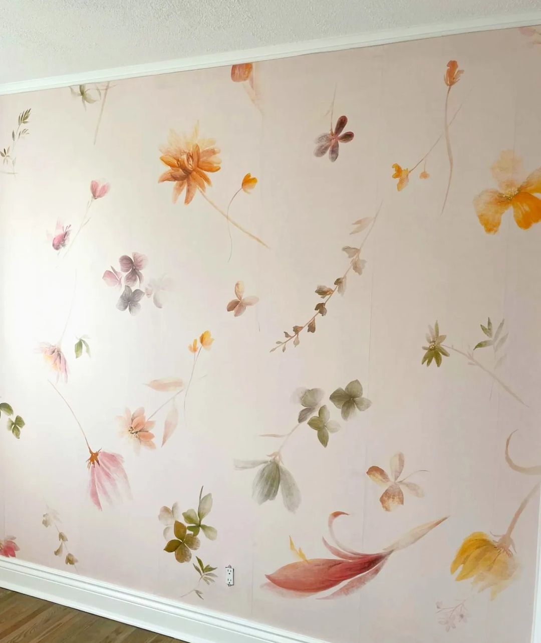 Papel tapiz floral en una pared, con flores y hojas estilo acuarela en tonos pastel.
