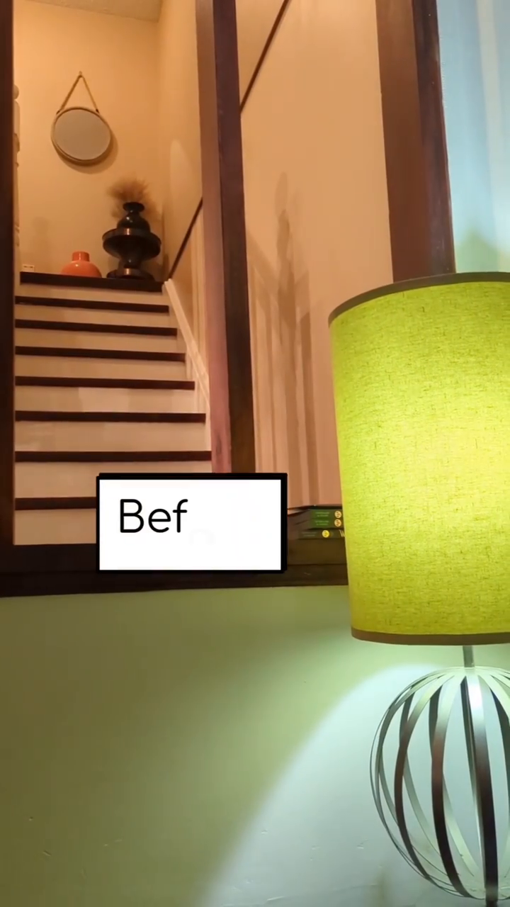 Interior view of staircase with decor, seen through mirror. "Before" text overlay. Green lamp in foreground.