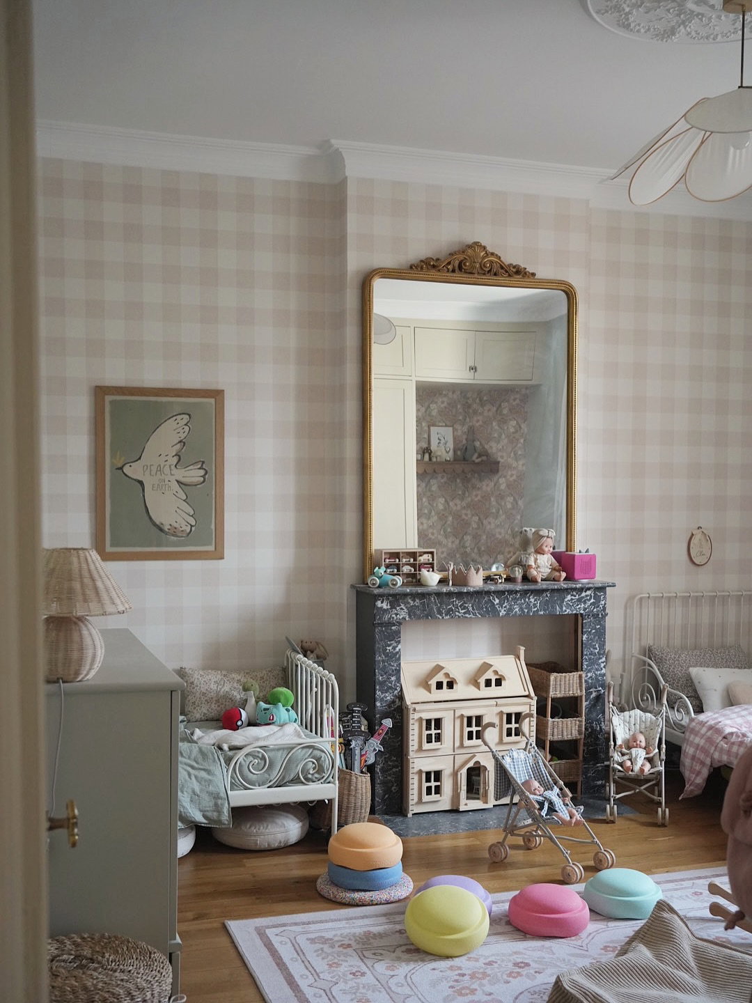 Children's bedroom with plaid wallpaper, a fireplace, dollhouse, and two twin beds.