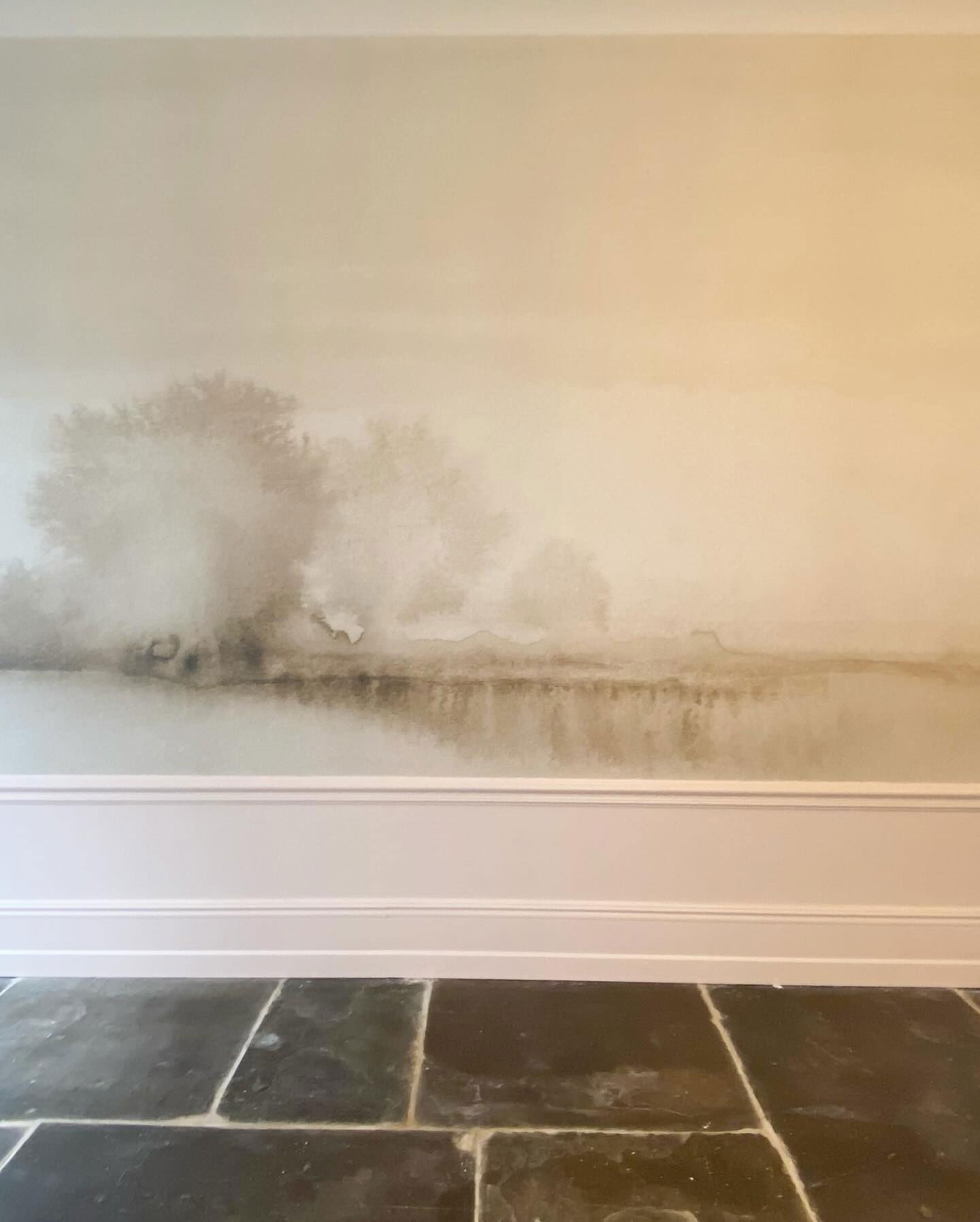 Binnenmuur met waterschade en schimmelvorming boven witte rand en donkere stenen tegelvloer.
