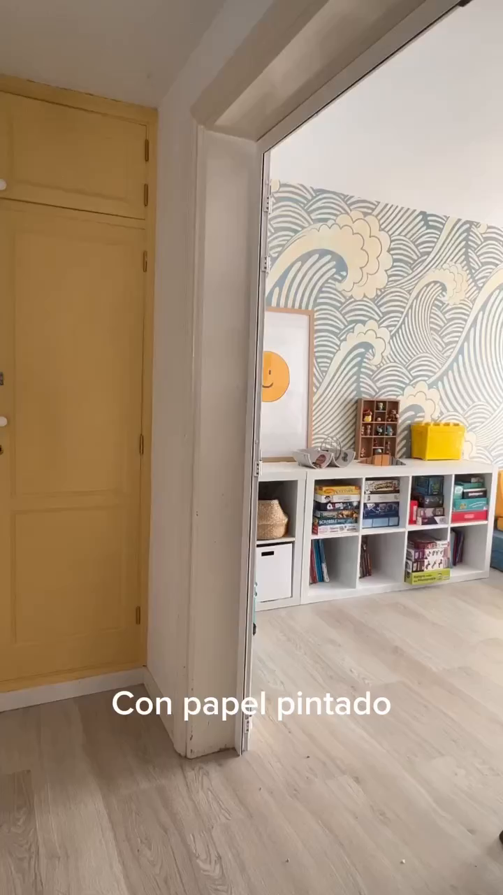 Interior view of a room with wave-patterned wallpaper and white shelving.