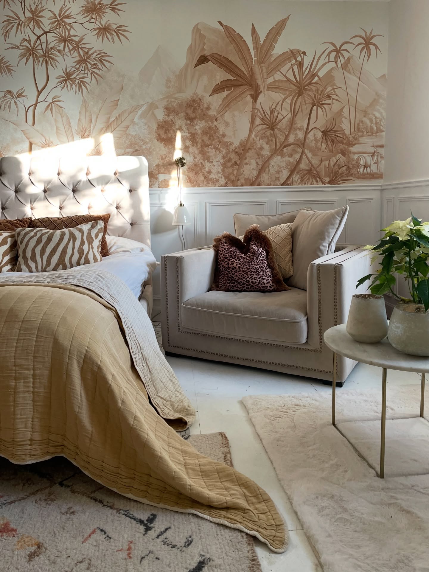 Bedroom scene with bed, chair, and tropical mural wallpaper.