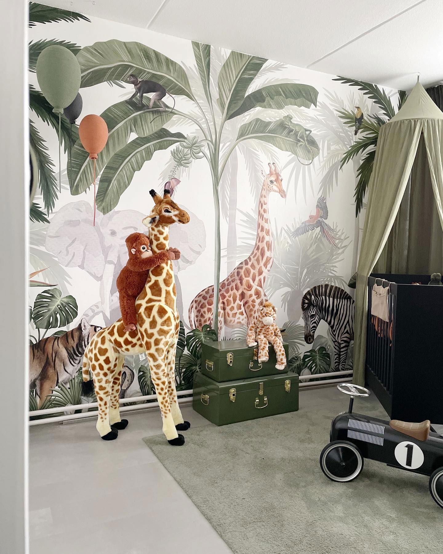 Barnerom med jungeltapet, utstoppet giraff med ape og svart barneseng.