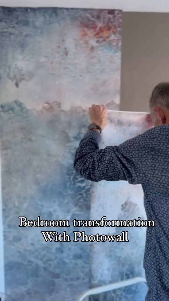 Enthusiastic woman in patterned suit presents bedroom with colorful mural.