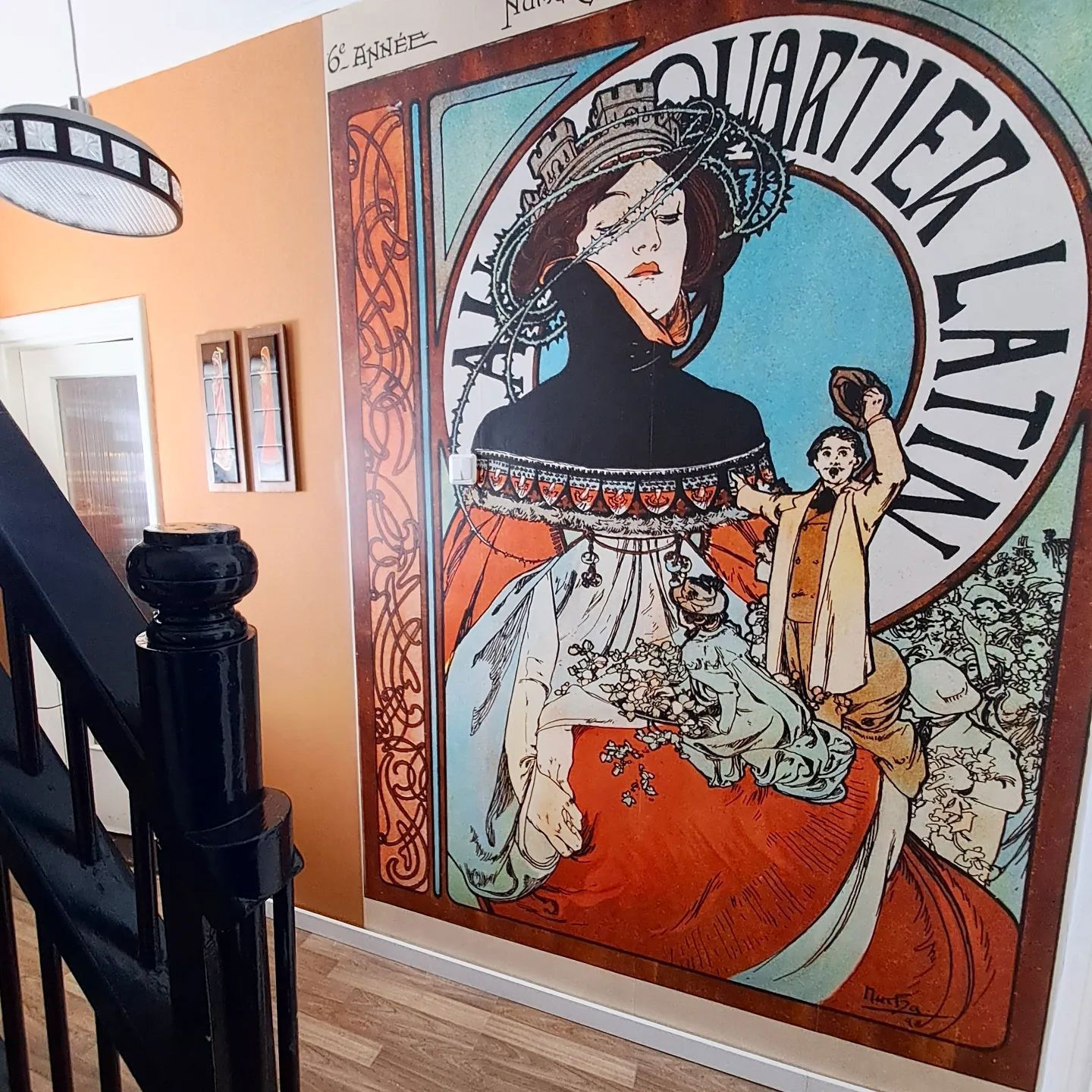 Hallway with black banister and large "Au Quartier Latin" Alphonse Mucha art nouveau poster.