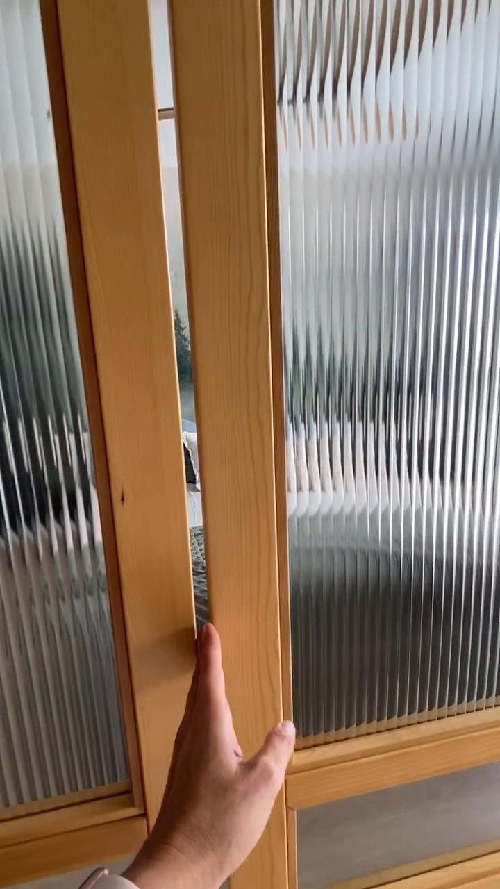 Hand closing a light wood frame glass door with reeded glass.