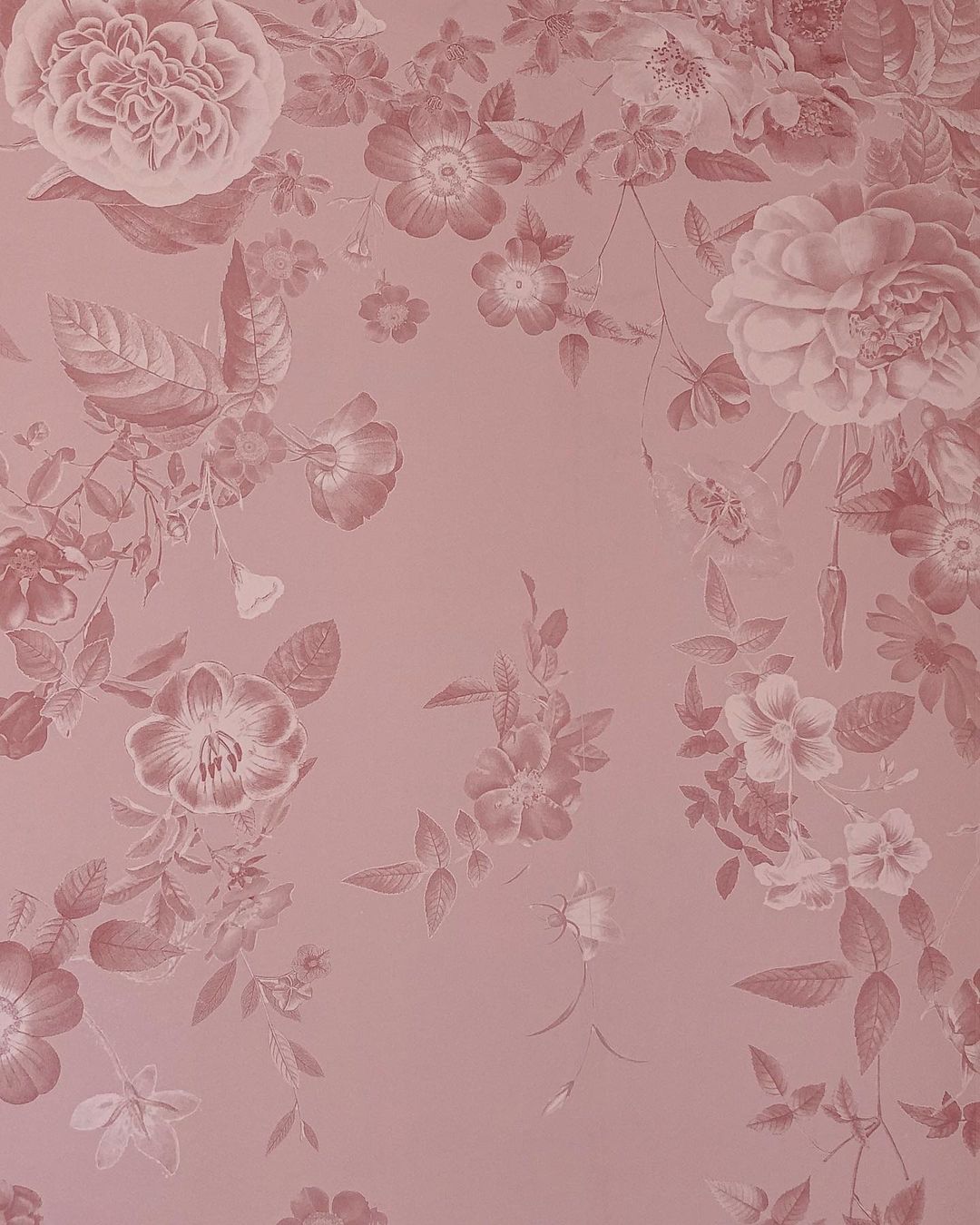 Stoffig roze behang met een bloemenmotief.