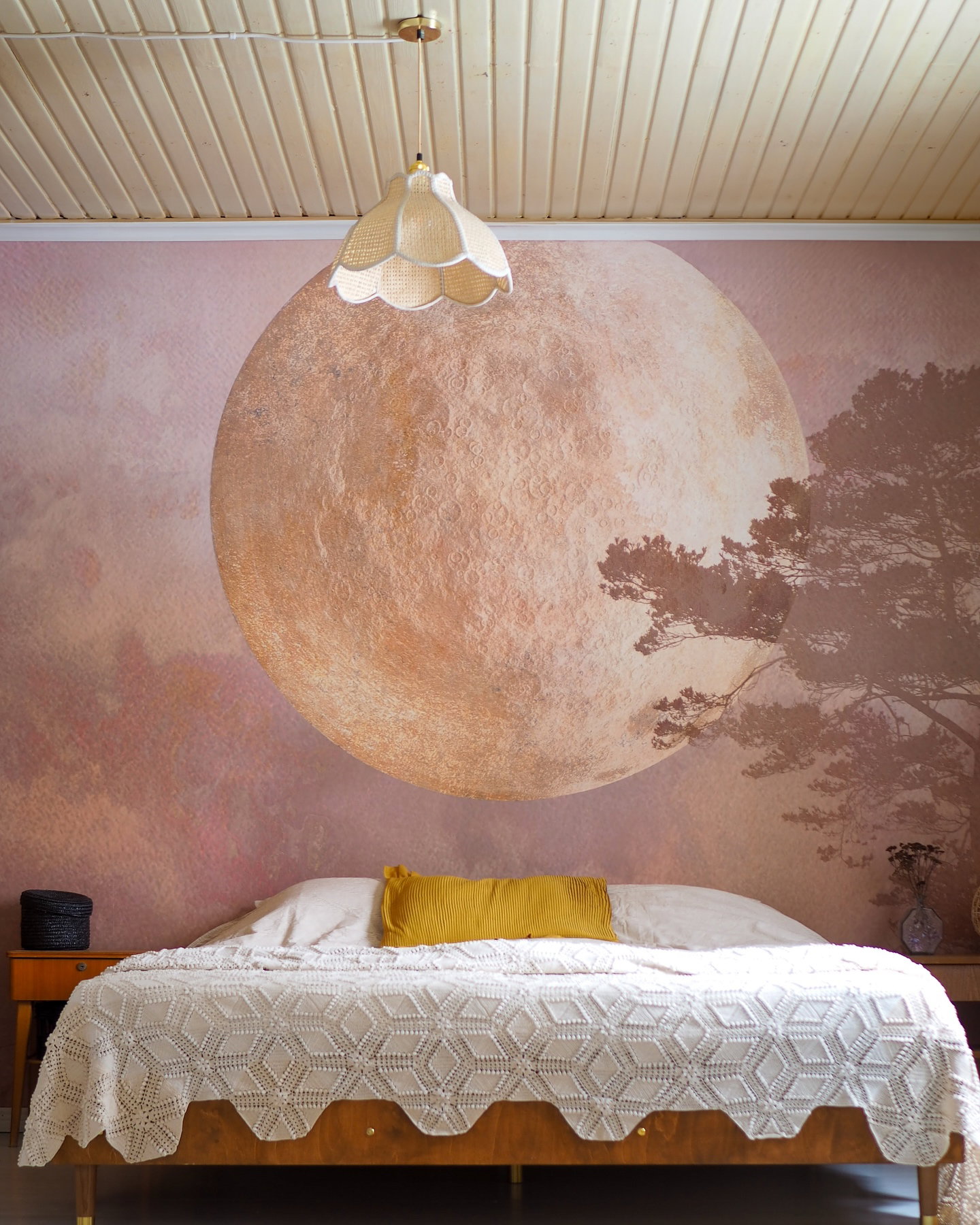 Bedroom with a large moon mural, bed with white bedding and yellow pillow.