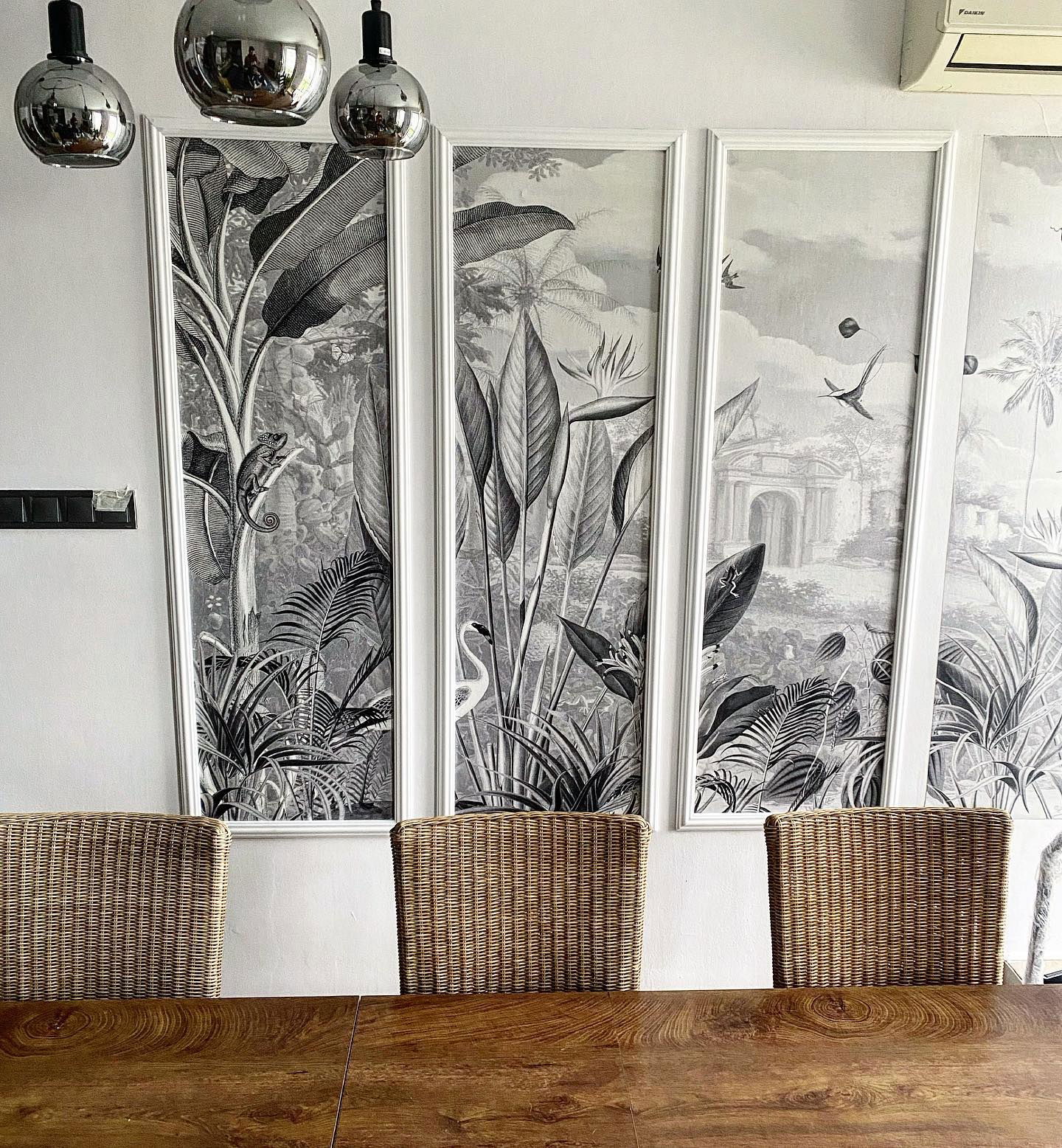 Dining room with wood table, wicker chairs, and framed tropical botanical prints.