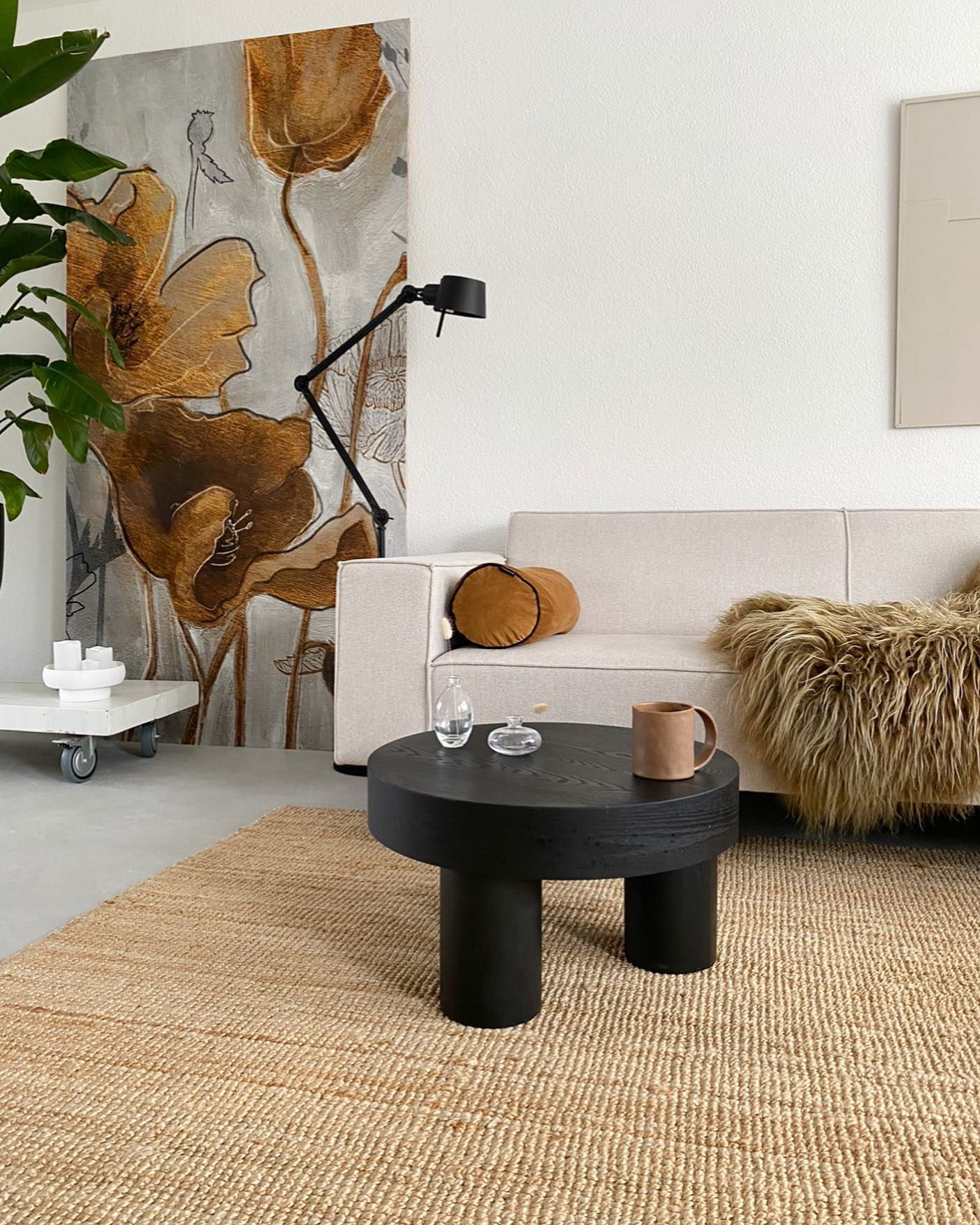 Living room scene with beige sofa, black coffee table, and floral wall art.