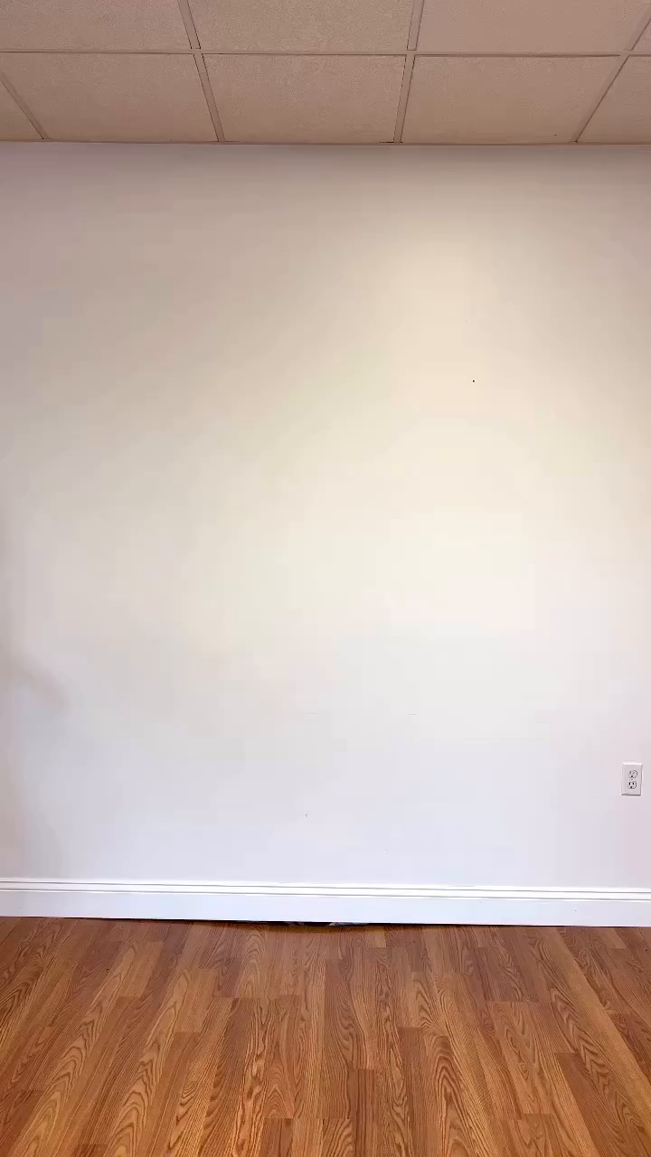 Empty room with wood floor, white walls, and a tiled ceiling.