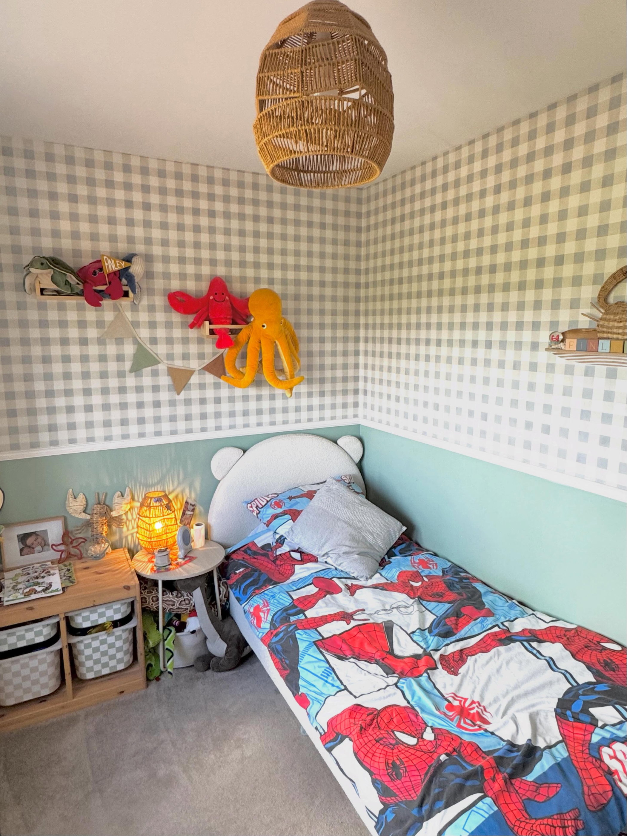 Children's bedroom with Spiderman bedding, plush sea creatures on shelves, and a woven pendant light.