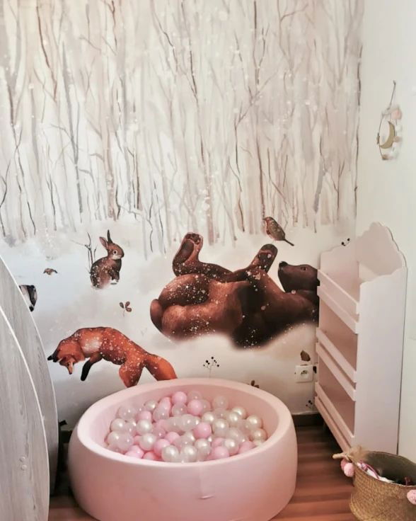Barnrum med tapet med skogsdjur, rosa bollhav och rosa bokhylla.