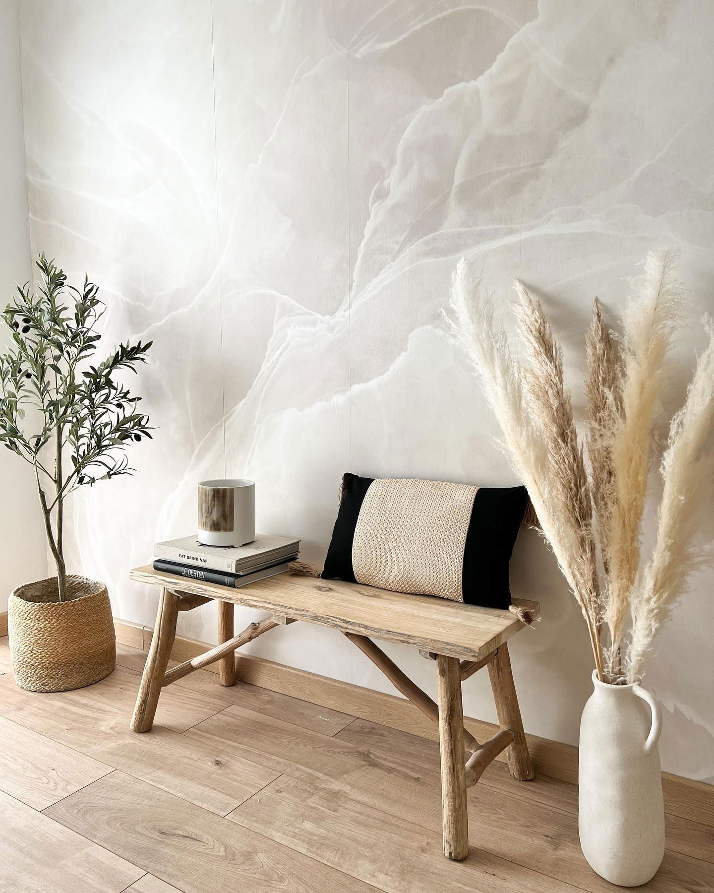 Interno con panca in legno, erba delle pampas in vaso e albero di ulivo. Tonalità neutre.
