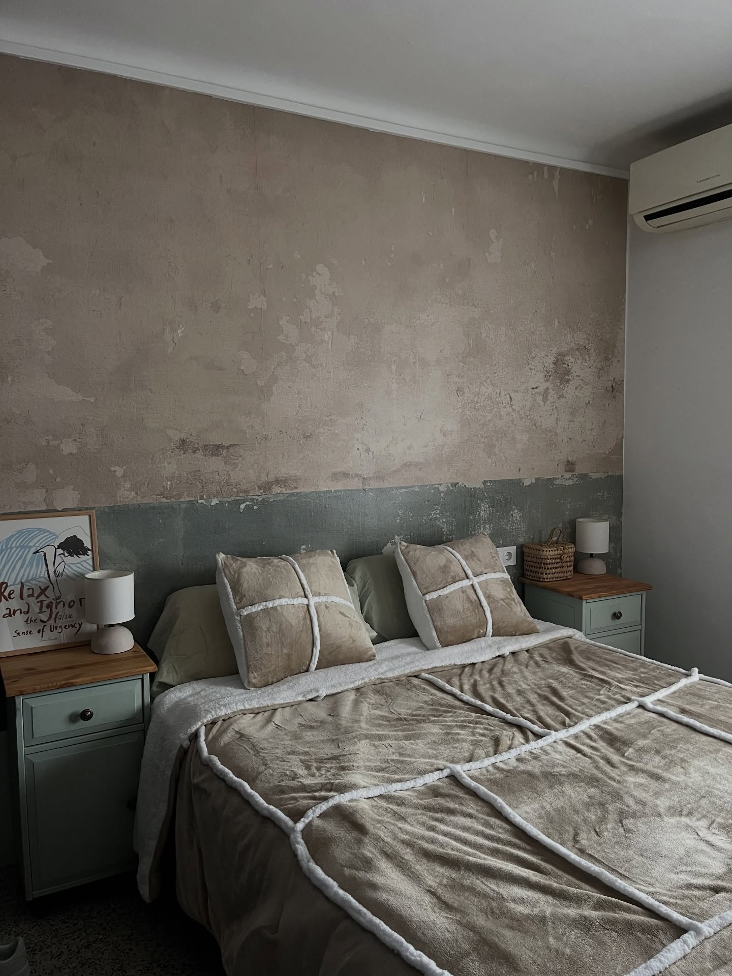 Bedroom with a textured wall, bed with beige and white bedding, and two green nightstands.
