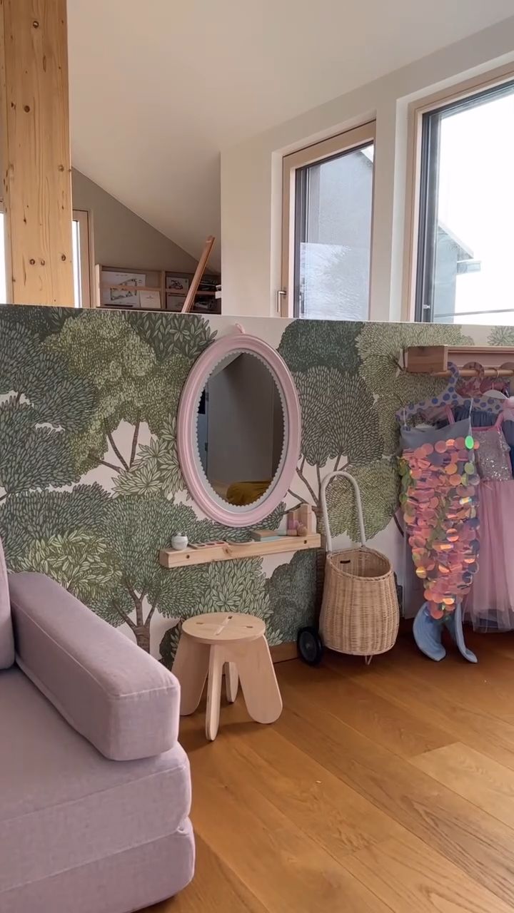 Interior view of a pink modular couch with round pillows, window view of trees.