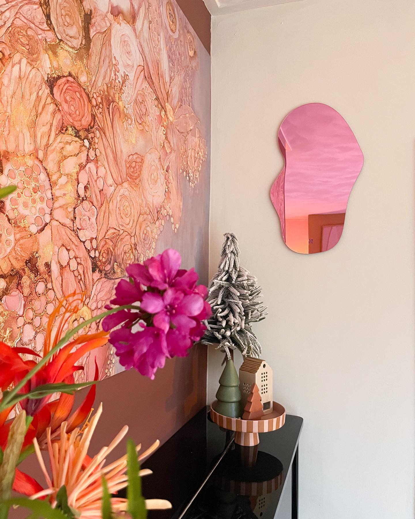 Interiør med rosa blob-speil, blomstertapet og festlig dekor.