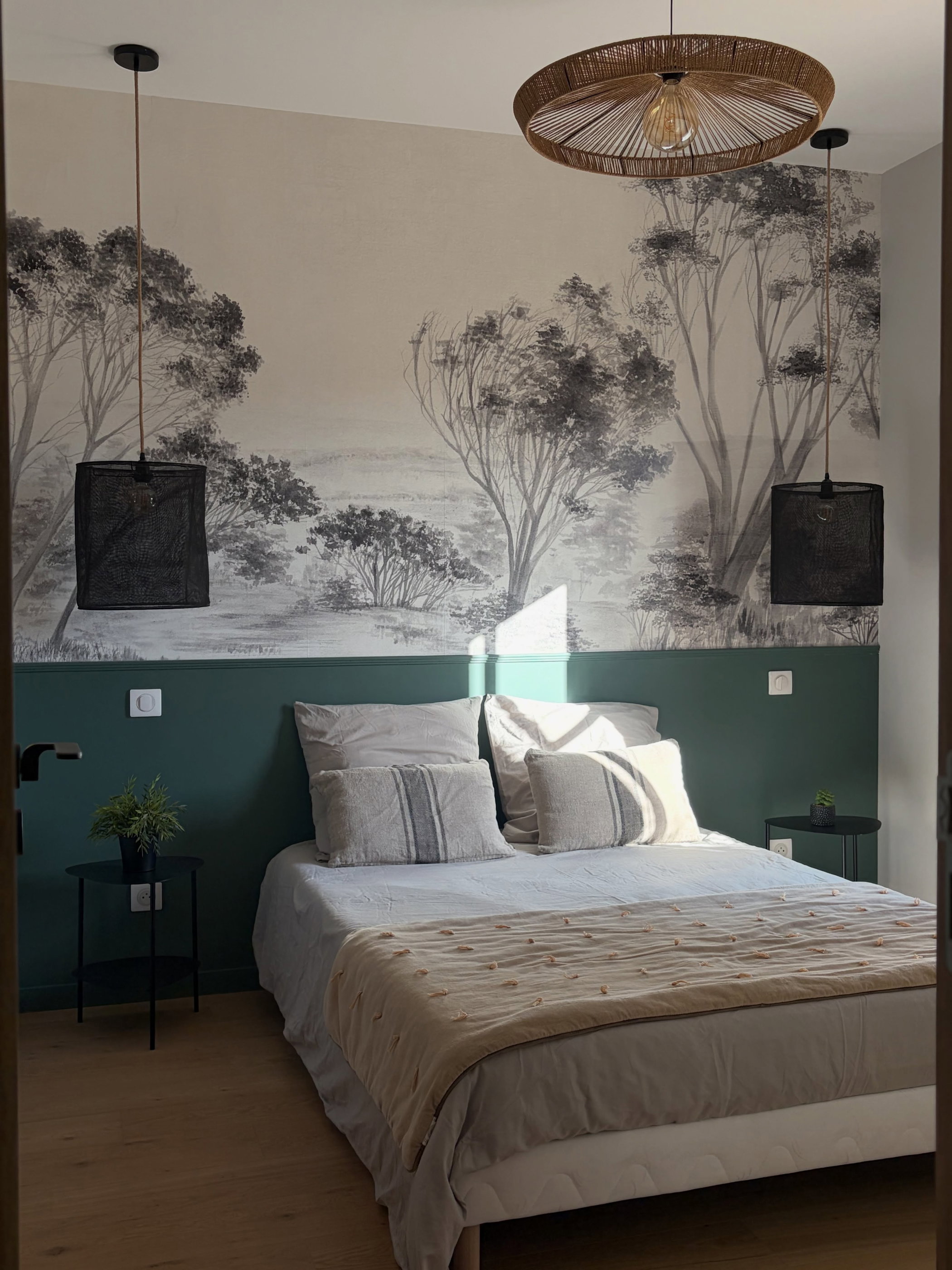 Bedroom with a landscape mural, a green accent wall, and a bed with neutral linens and pillows.