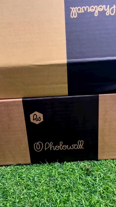 Stacked Photowall boxes on green grass.