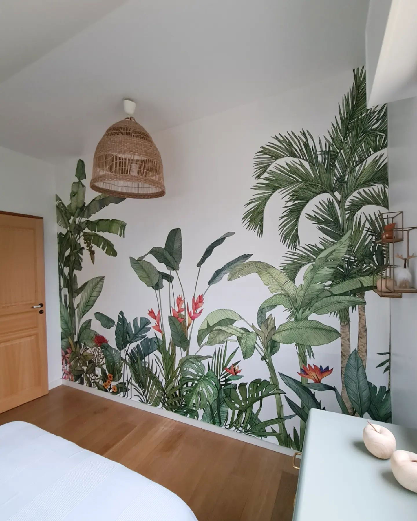 Bedroom with tropical mural, wood floors, and woven pendant light.