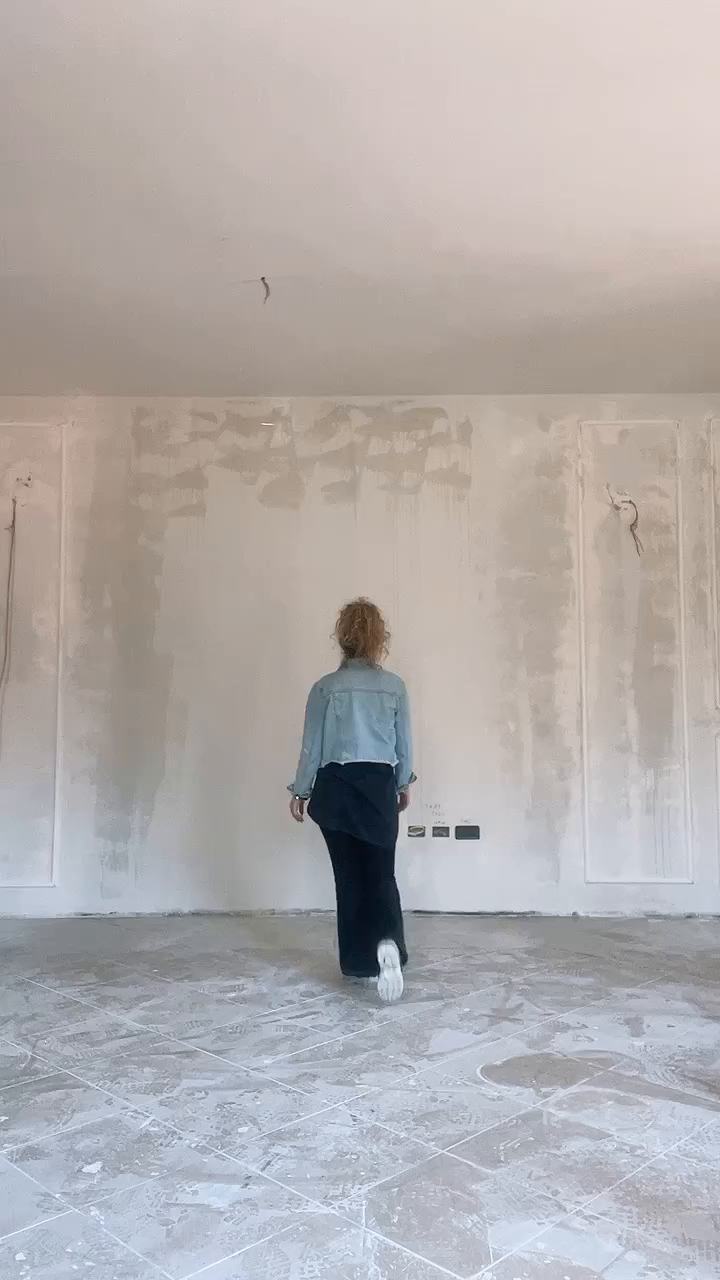 Back view of a woman in a denim jacket in a room under construction.