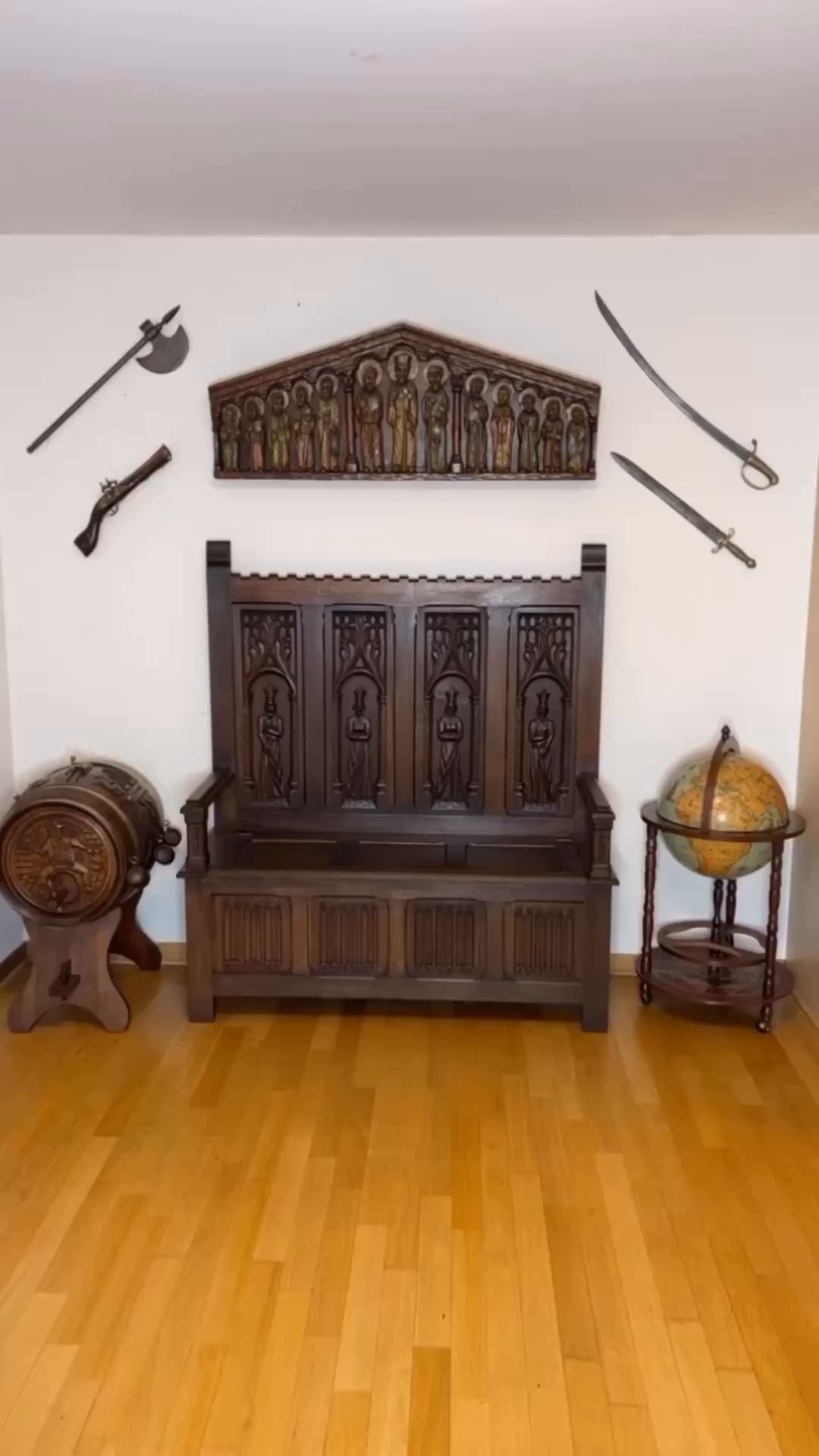 Interior with antique wooden bench, globe, barrel, and weapons on the wall.