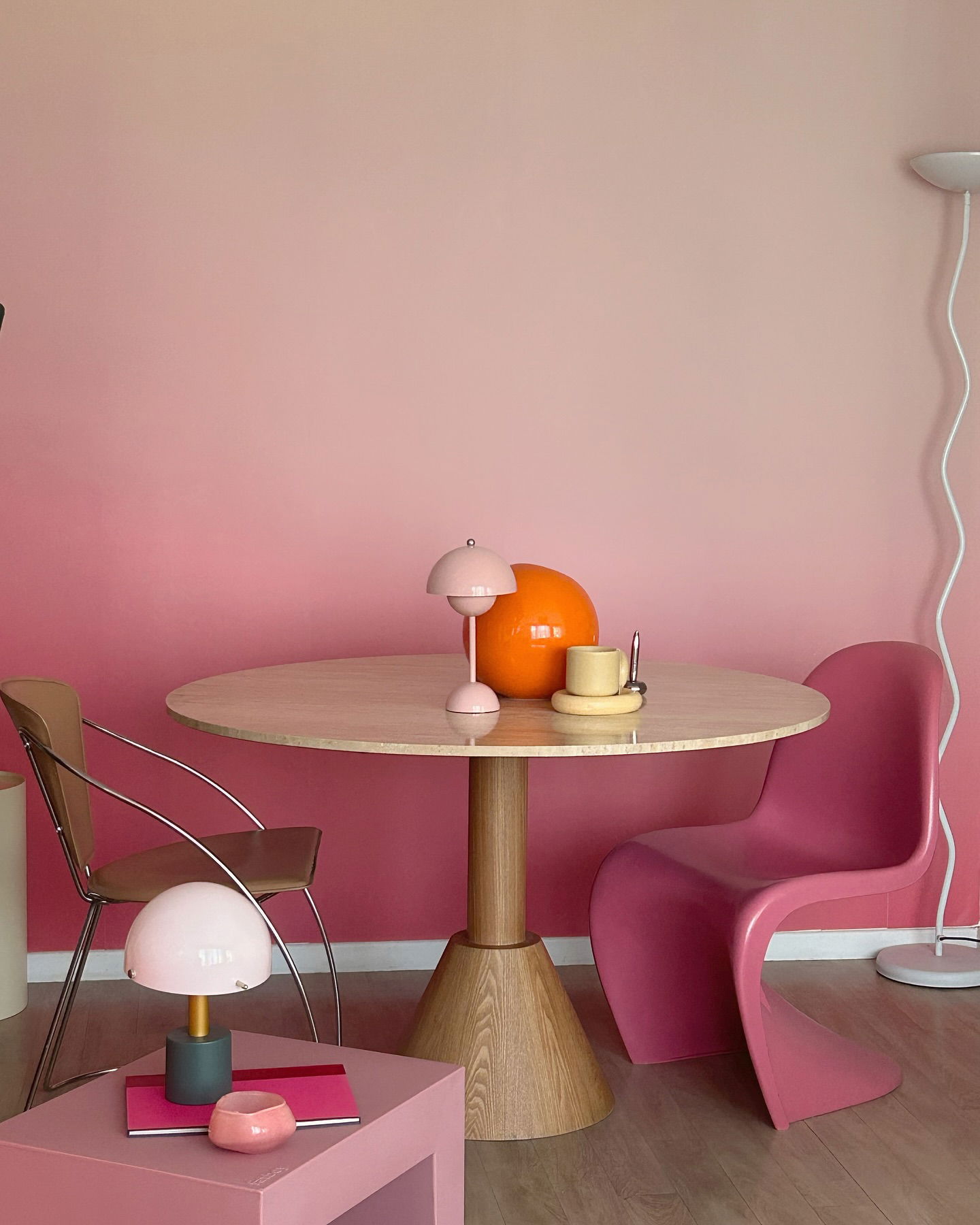 Interieur mit rosa Ombré-Wand, rundem Tisch, rosa Panton-Stuhl und rosa Beistelltisch mit Pilzlampe.