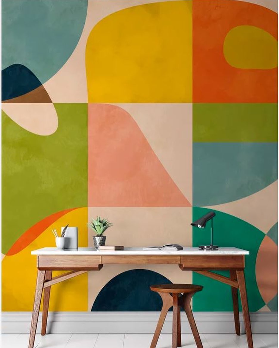 Home office with mid-century desk, stool, and colorful geometric wallpaper.