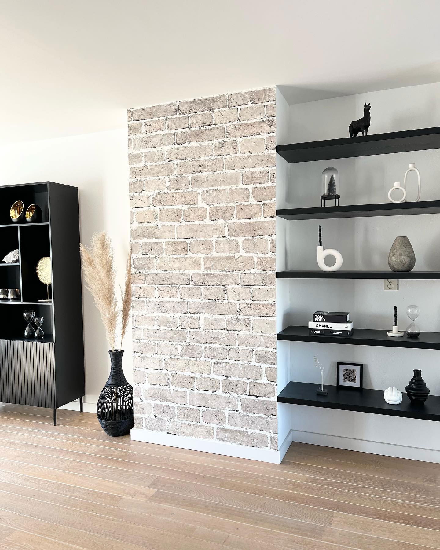 Living room with black shelving, decor, and brick accent wall.