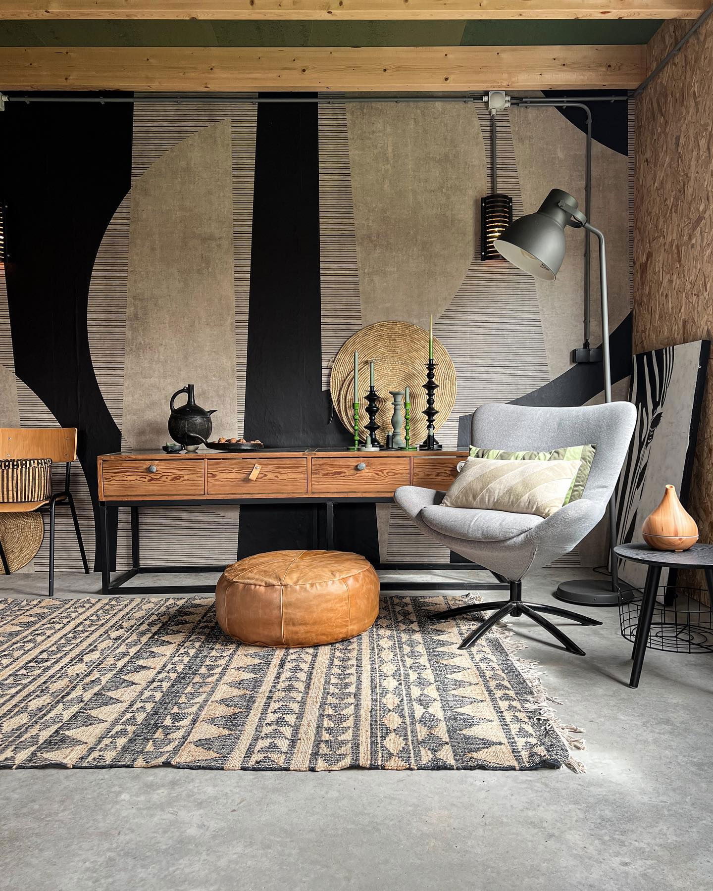 Living room with patterned rug, leather pouf, gray chair, and wood console table.