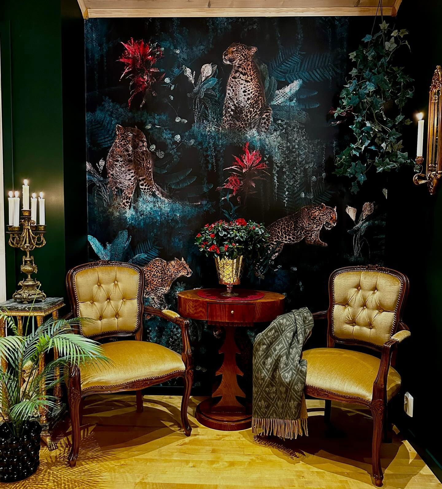 Living room with leopard print wallpaper, two gold chairs, and a small wooden table.