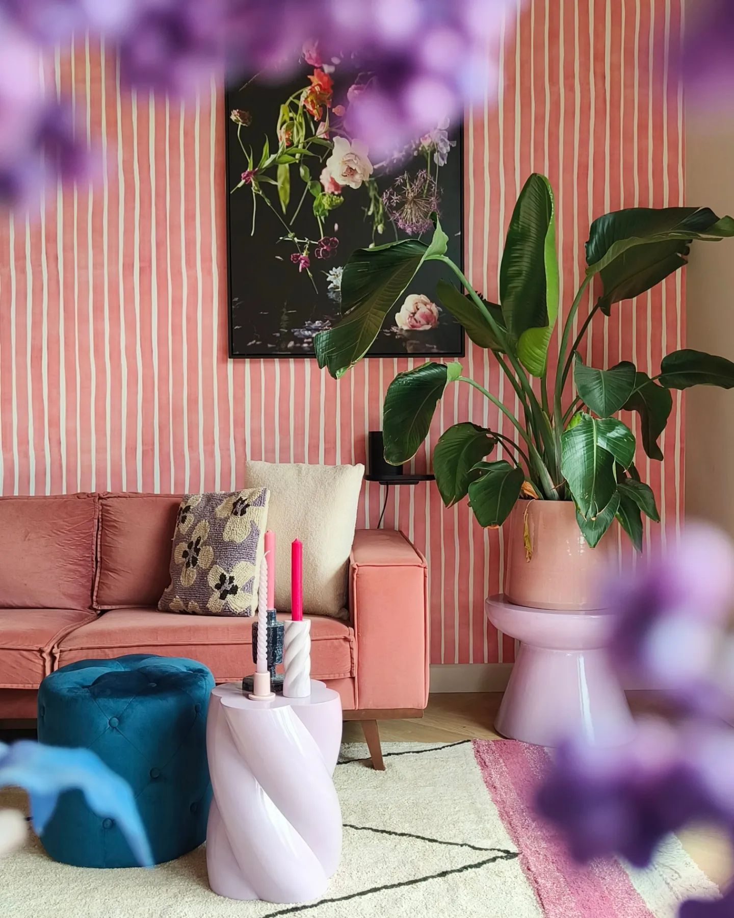 Living room with pink striped wallpaper, pink couch, and a large potted plant.
