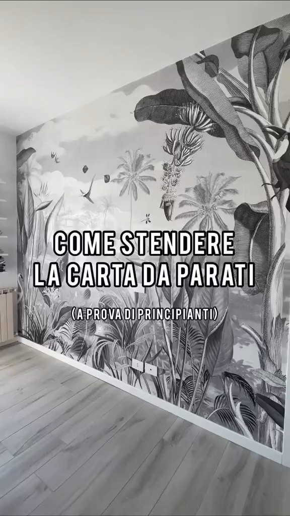 Monochrome tropical wallpaper on a wall with light wood floors.