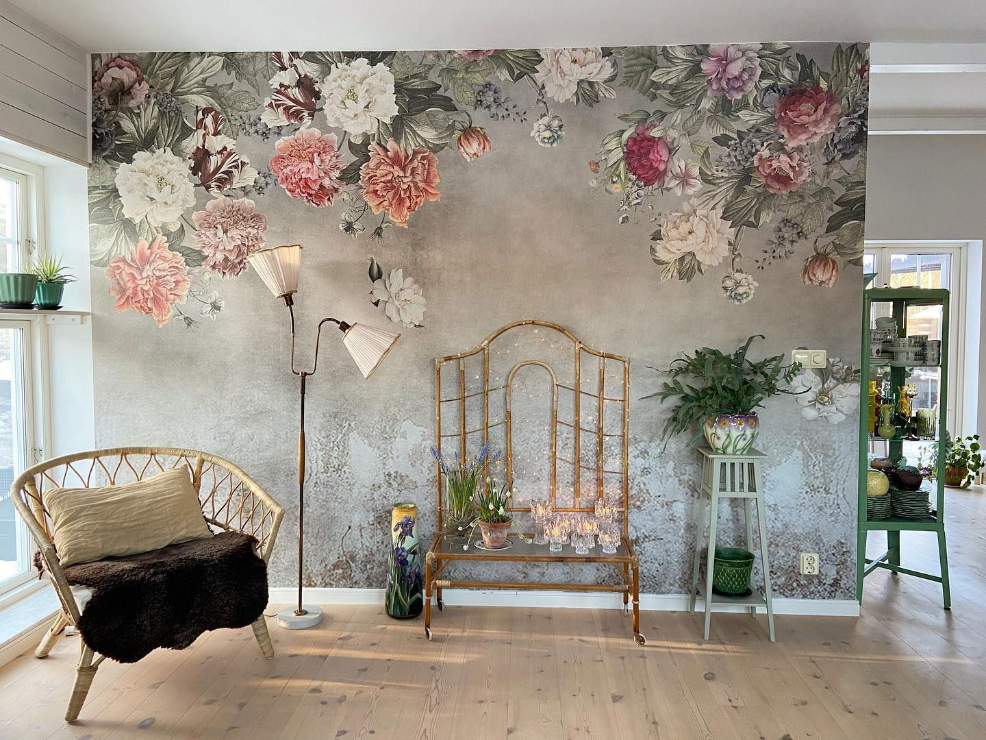 Ekscentryczny salon z tapetą w kwiaty, wiklinowym krzesłem i wystrojem w stylu vintage.