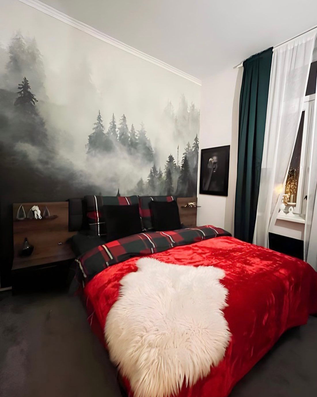Schlafzimmer mit roter Decke, karierter Bettdecke und Waldgemälde.