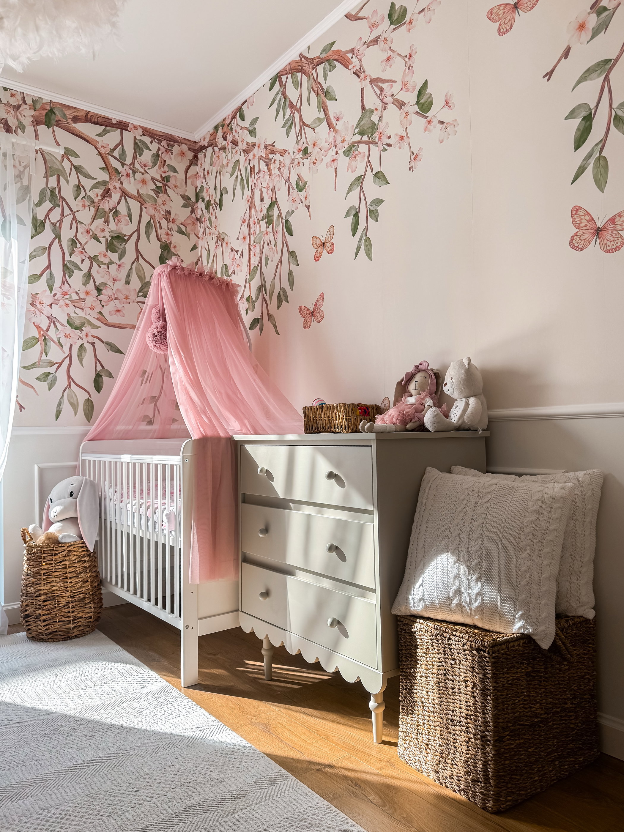 Nursery with cherry blossom wallpaper, crib, and dresser.