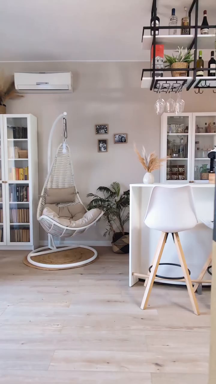 Living room with hanging chair, white bar with stools, and built-in shelving.