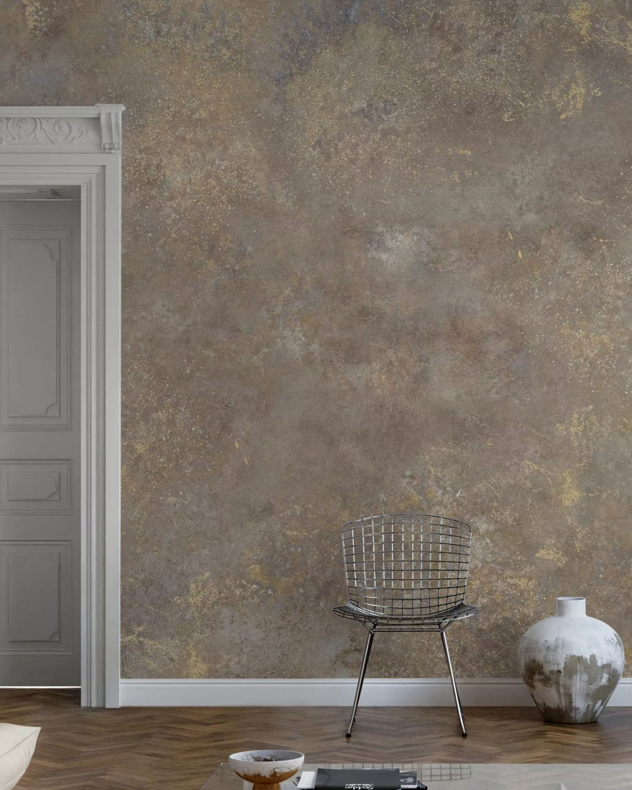 Interior with textured brown wall, white door frame, wire chair, and decorative vase.