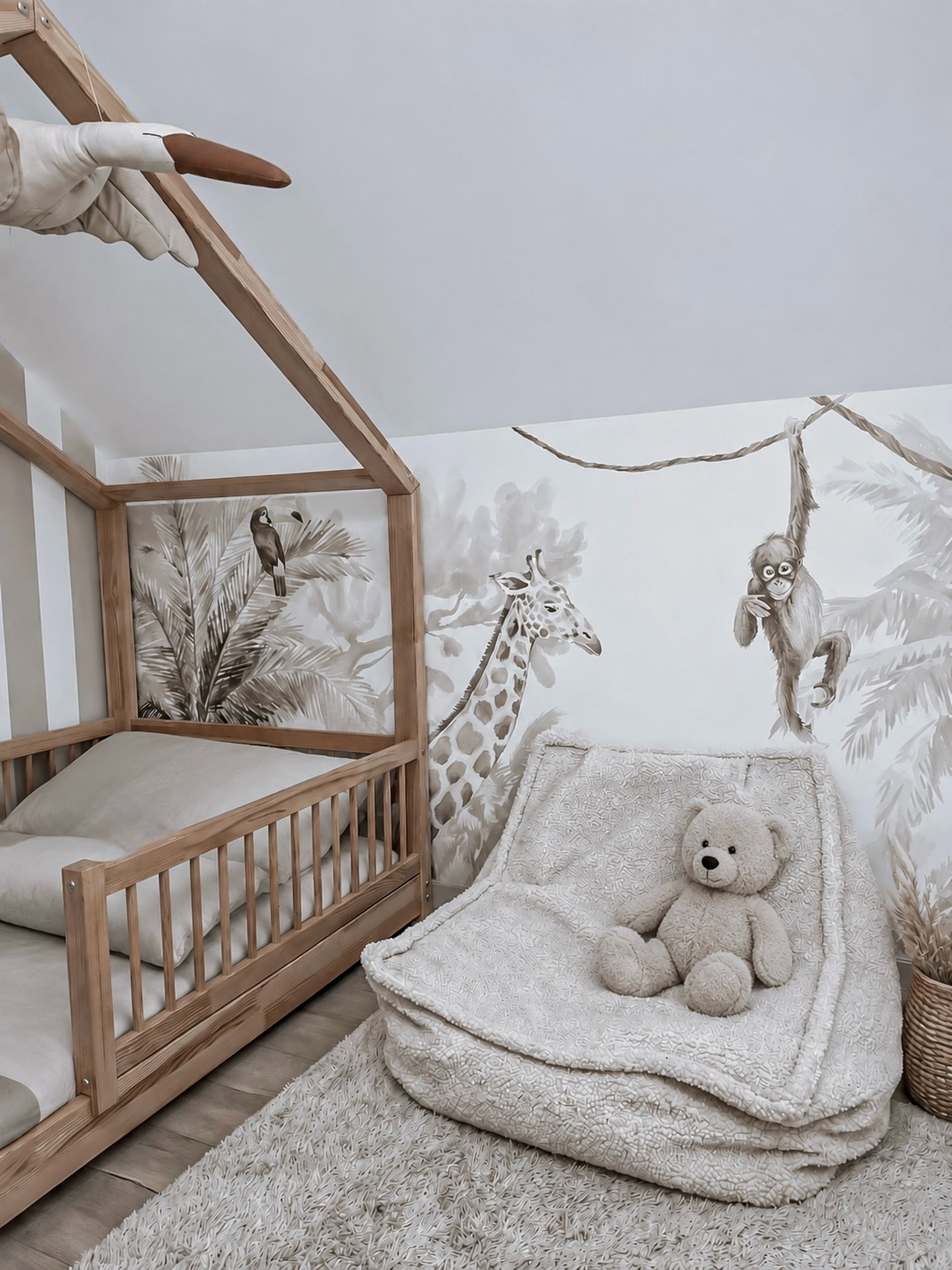 Children's bedroom with safari mural, wooden bed, and fluffy beanbag chair with teddy bear.