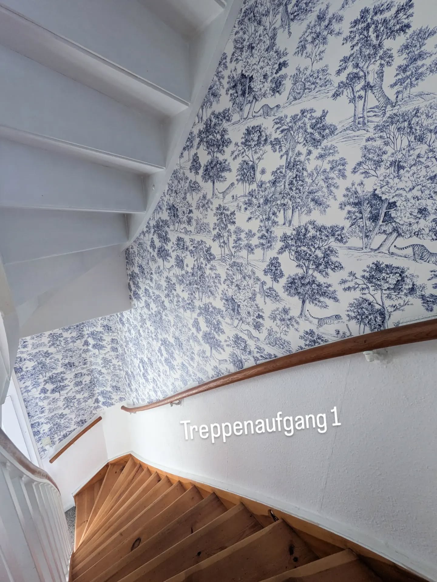 Wooden stairs with a blue and white toile wallpaper featuring trees and animals.