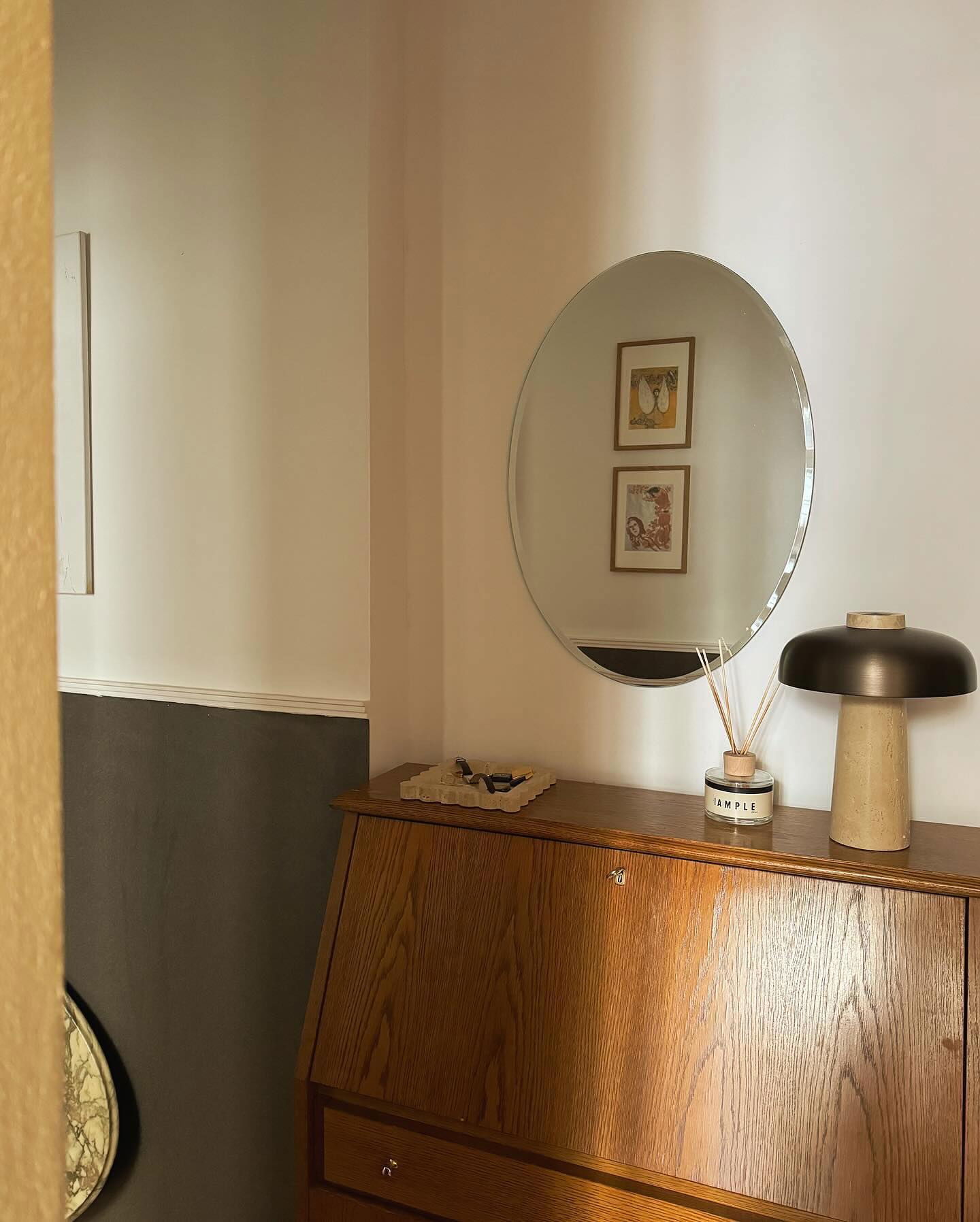 Innenansicht eines Holzschreibtisches mit rundem Spiegel, Lampe und Diffusor.