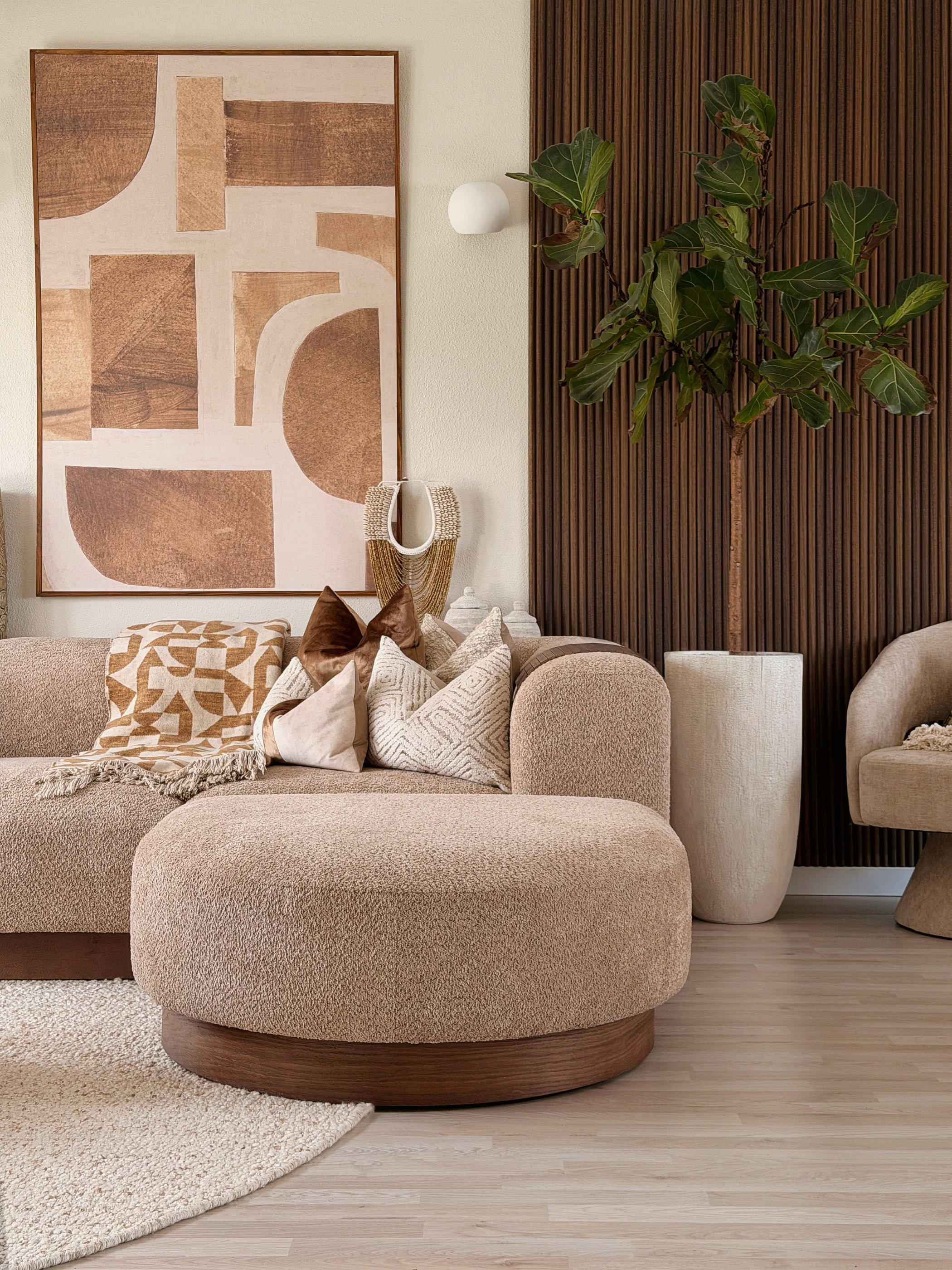 Living room with textured tan sofa, ottoman, and modern abstract art.