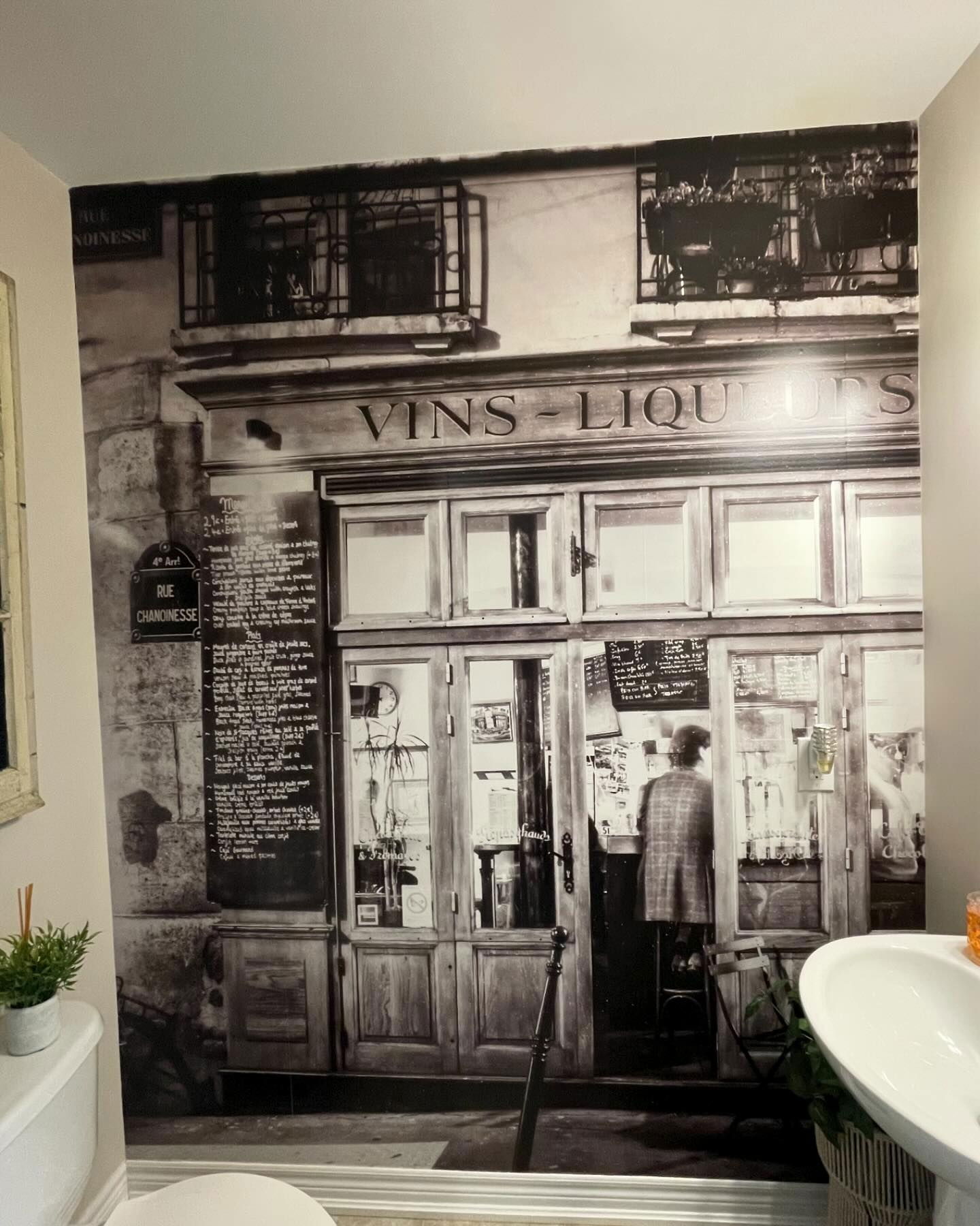 Badkamer met een zwart-wit muurschildering van een Parijse wijnwinkel.